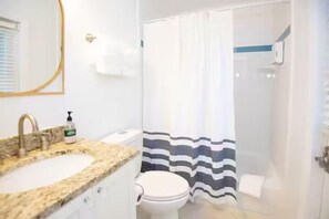 Une salle de bain équipée d’un lavabo, de toilettes et d’un rideau de douche.