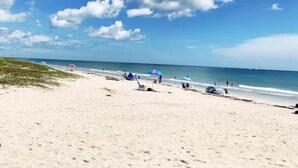 Une plage de sable, quelques parasols et un ciel dégagé.