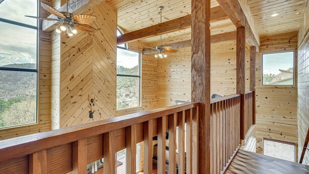A wooden interior with a herringbone ceiling, wooden railings, and large windows offering a view of the outdoors. - Gorgeous 4-bedroom cabin in enjoyable Summerhaven getaway +game room (Summerhaven)