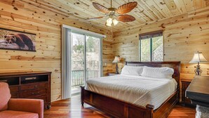 A wooden cabin bedroom with a bed, a desk, a chair, and a ceiling fan. - Gorgeous 4-bedroom cabin in enjoyable Summerhaven getaway +game room (Summerhaven)