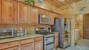 A kitchen with wooden cabinets, stainless steel appliances including a microwave, toaster, stove, and refrigerator. - Gorgeous 4-bedroom cabin in enjoyable Summerhaven getaway +game room (Summerhaven)