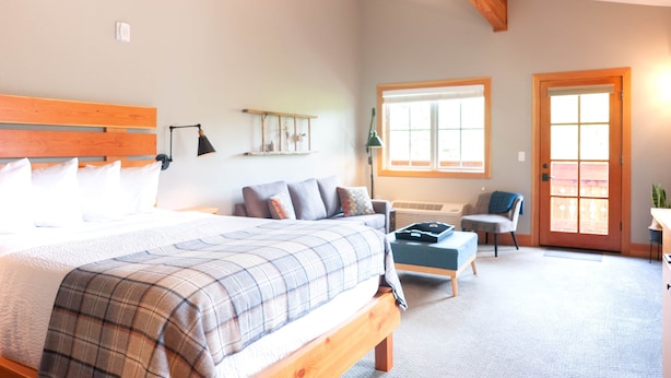 A bedroom with a large bed, a desk, a chair, and a window. - Studio 5 @ The Suites on Main (Leavenworth)