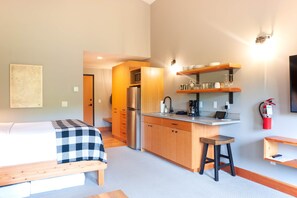 Une chambre d’hôtel moderne équipée d’un lit, d’une kitchenette et d’un petit coin repas.