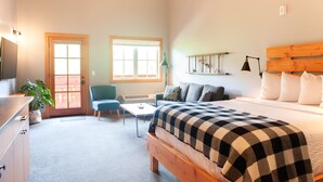 A bedroom with a bed, a desk, a chair, a sofa, and a window.