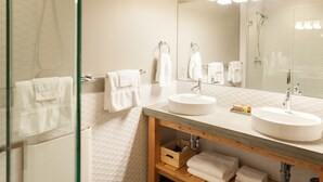 A modern bathroom with two sinks, a large mirror, and a glass shower enclosure. - Studio 2 @ The Suites on Main (Leavenworth)