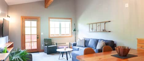 Ein Wohnzimmer mit einer Couch, einem Esstisch, einem Couchtisch und einem Fernseher.
