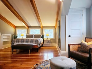 Een slaapkamer met een bed, nachtkastjes, een stoel en een raam.