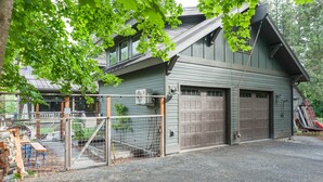A two-story building with a garage and a fenced area with a gate. - The Alley House (Leavenworth)