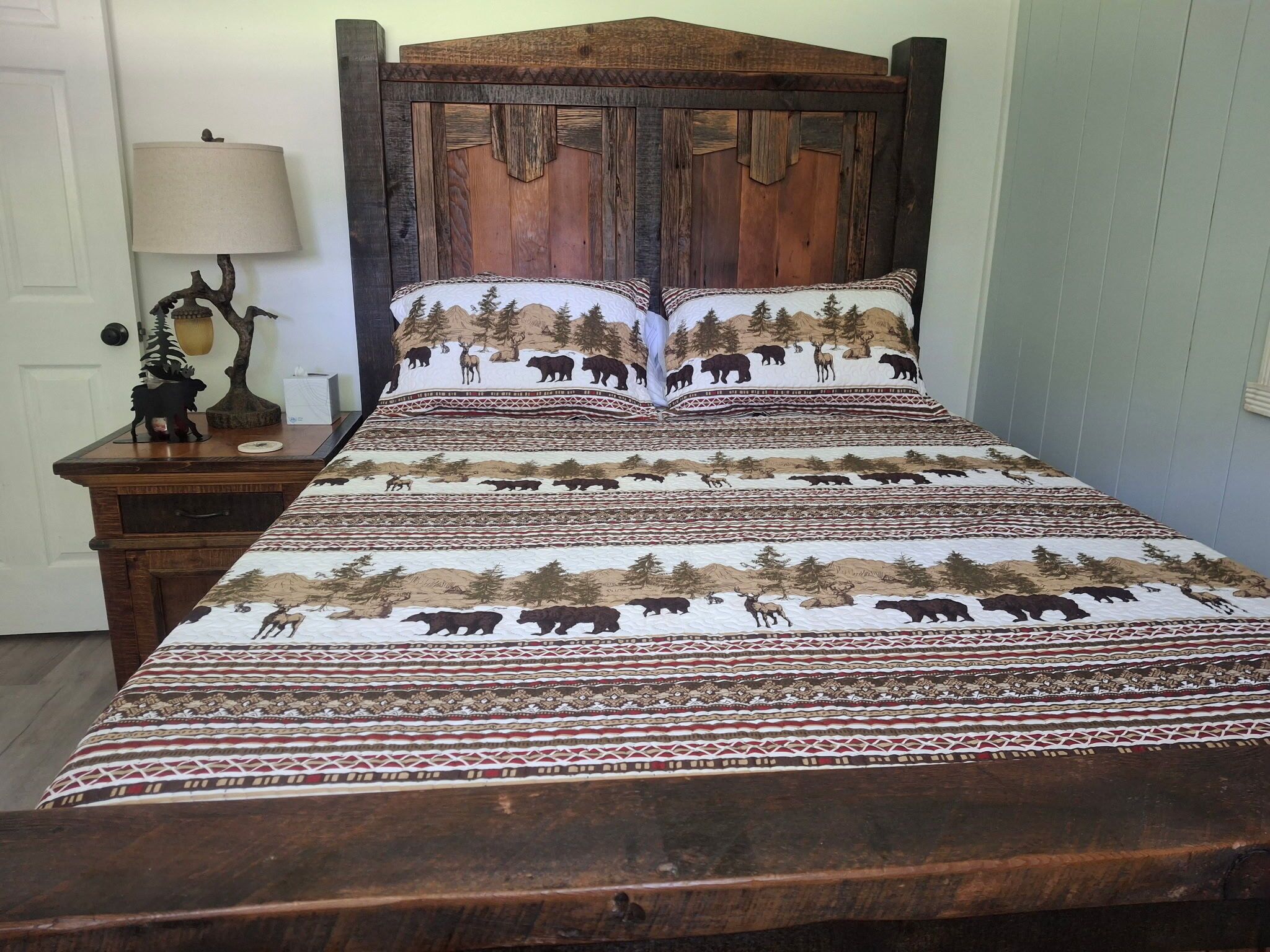 A bed with a wooden headboard and a patterned bedspread featuring wildlife.