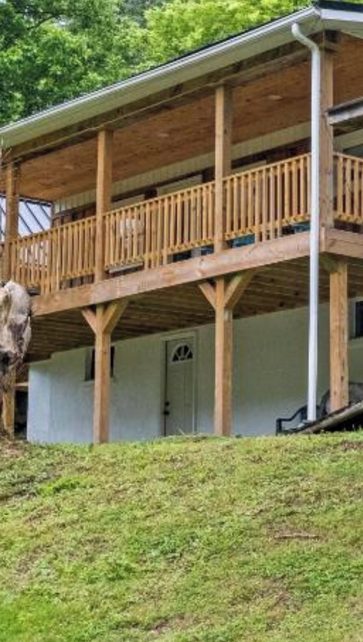 Un edificio de madera de dos pisos con un balcón, una puerta y un ventanal pequeño.