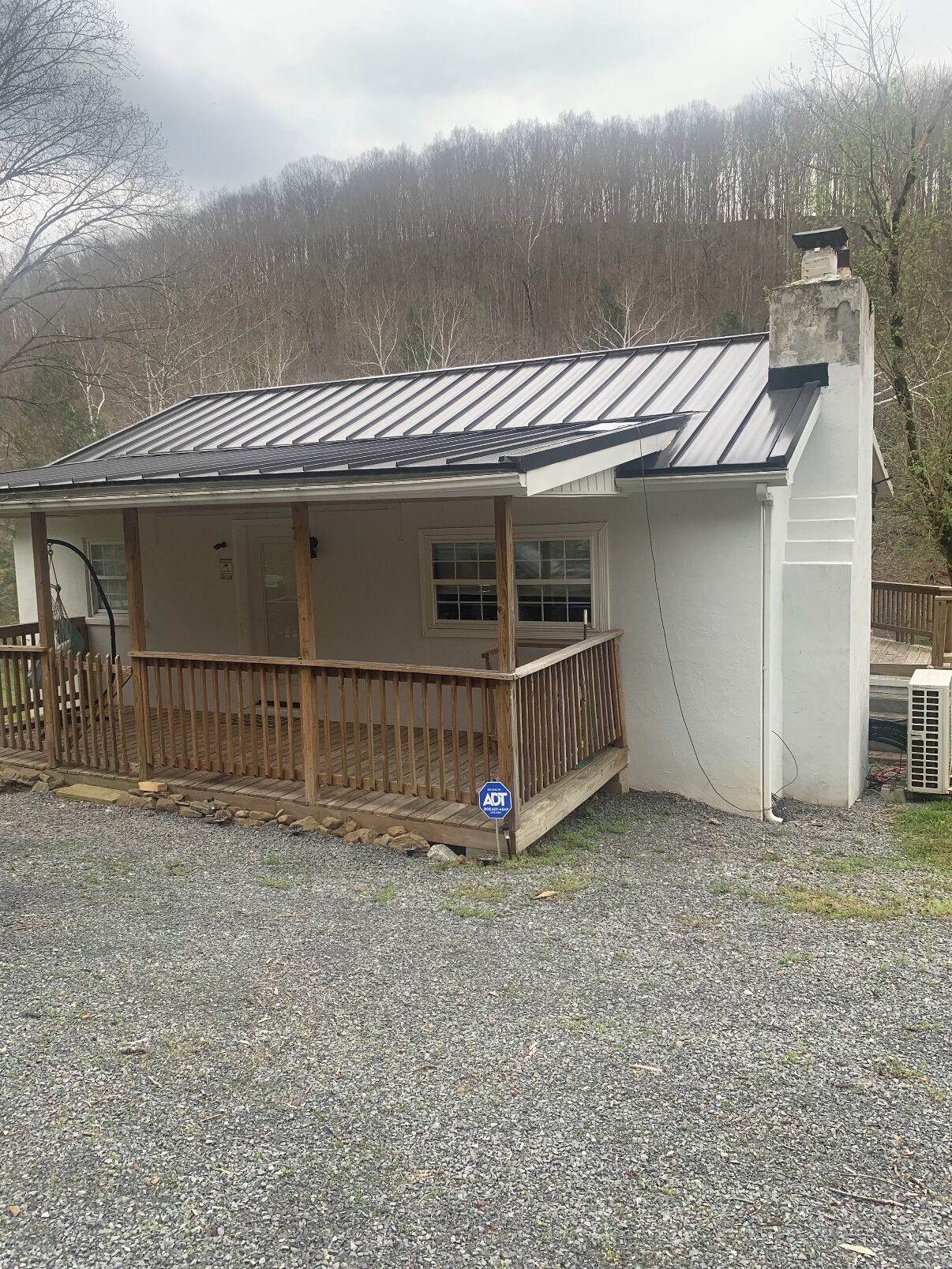 A single-story building with a covered porch, a chimney, and a gravel driveway.