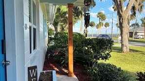 Una casa con un cartello 'WELCOME', un portico e vista su alberi e una strada.