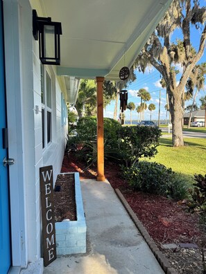 A house with a 'WELCOME' sign, a porch, and a view of trees and a road. - Peaceful 3-bedroom house in Port Orange/South Daytona Beach (Port Orange)