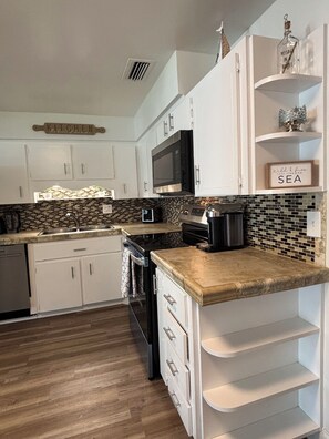 A kitchen with white cabinets, a microwave, a coffee maker, and a tiled backsplash. - Peaceful 3-bedroom house in Port Orange/South Daytona Beach (Port Orange)