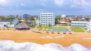 Un hotel frente a la playa con piscina, bar en la playa y muelle para embarcaciones.