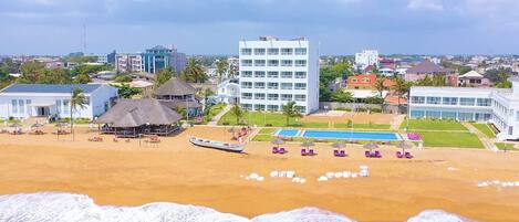 A beachfront hotel with a swimming pool, a beach bar, and a boat dock.