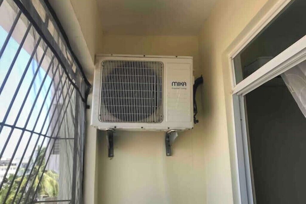 Une pièce dotée d’une fenêtre, d’une porte et d’un climatiseur fixé au mur.