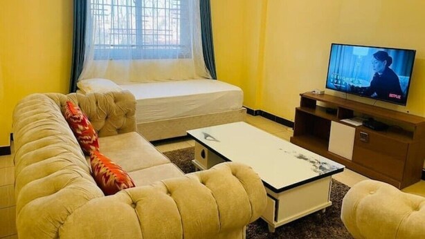 Een woonkamer met een bank, een salontafel, een televisie en een bed.