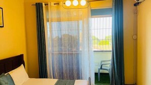 Een hotelkamer met een bed, een raam met gordijnen en uitzicht op buiten.