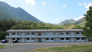 A motel with a simple, two-story structure, a parking lot, and a mountainous backdrop. - Retasket Lodge & RV Park (Lillooet)