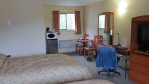 A hotel room with two beds, a desk with a chair, a television, and a window with curtains. - Retasket Lodge & RV Park (Lillooet)