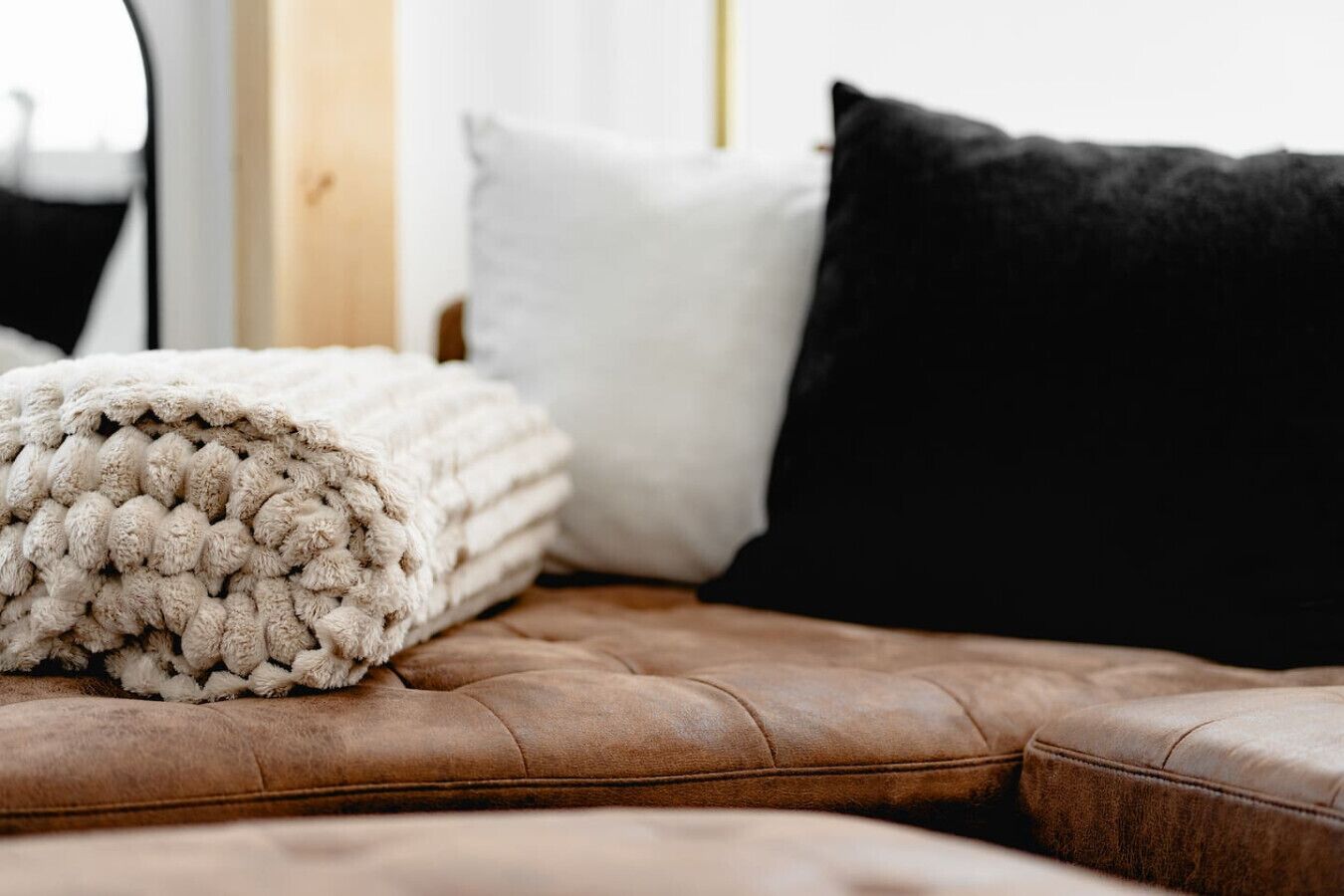 Un lit avec une couverture pliée, un oreiller blanc et un oreiller noir.