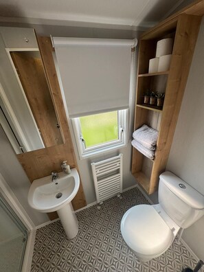Een kleine badkamer met een wastafel, toilet en een klein raam.