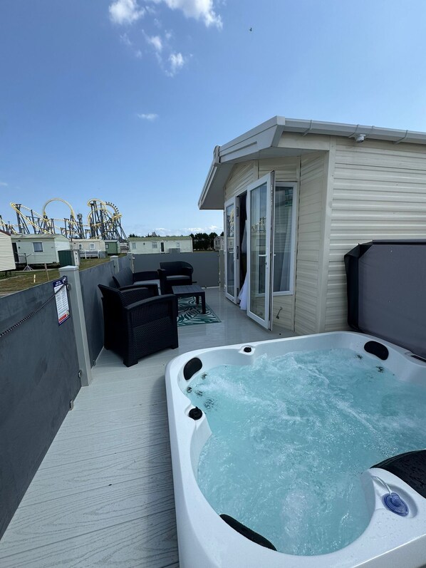 Een dak terras met een jacuzzi, buiten meubels en uitzicht op attracties van een pretpark.