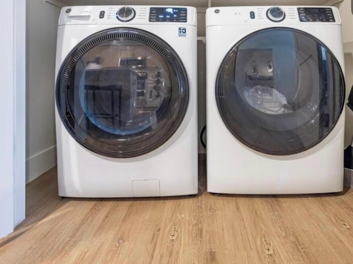 Two front-loading washing machines in a room with wooden flooring.