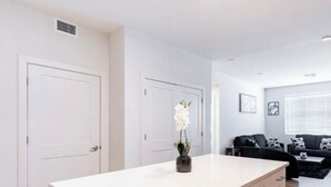 Een moderne keuken met een wit aanrecht, beige kastjes en een kleine potplant.