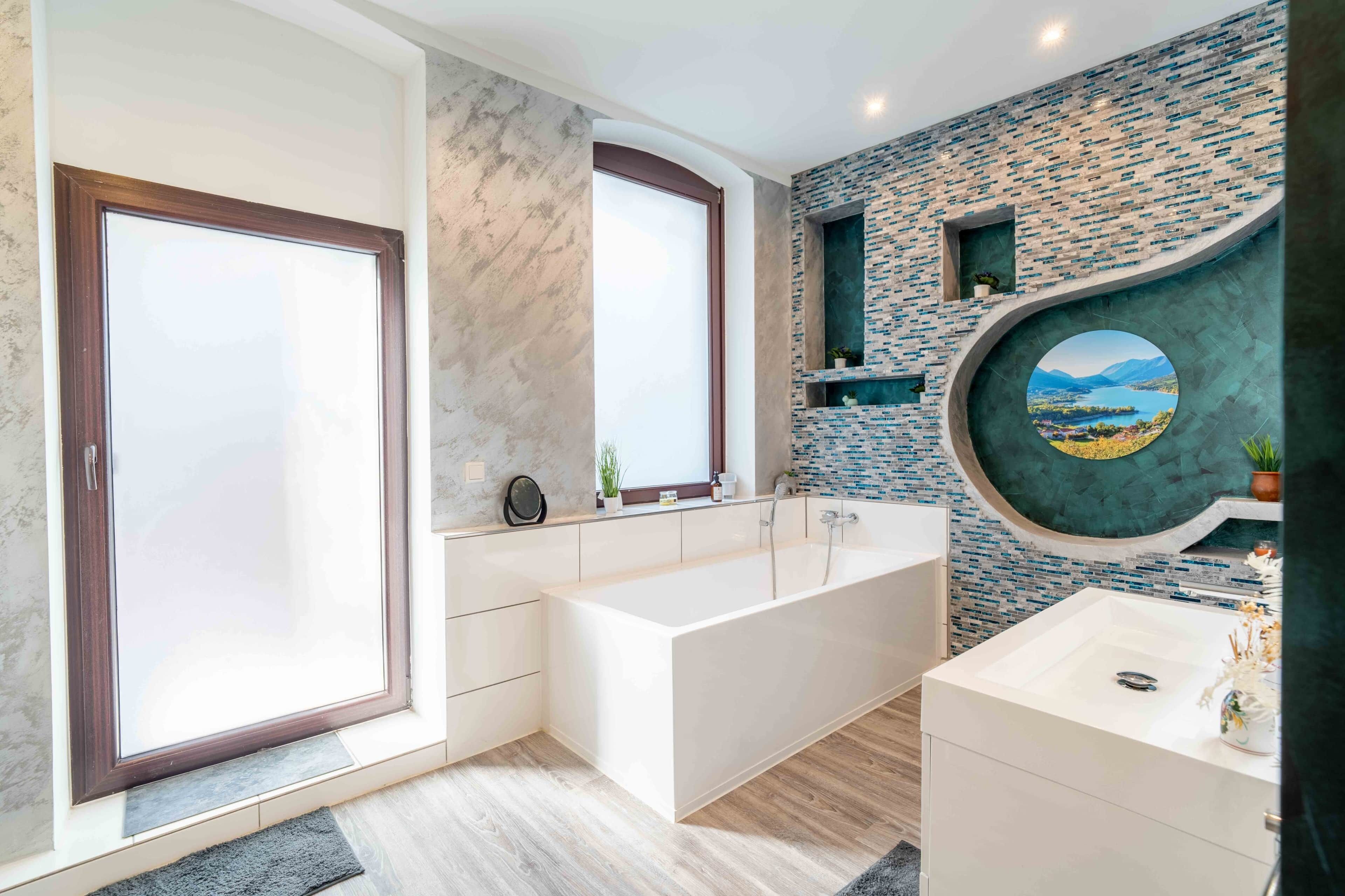 Un baño moderno con una bañera grande, un lavabo y una ventana con vistas a las montañas.