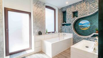 Un baño moderno con una bañera grande, un lavabo y una ventana con vistas a las montañas.