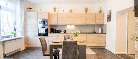 Una cocina moderna con armarios de madera, una mesa de comedor, sillas y un horno empotrado.