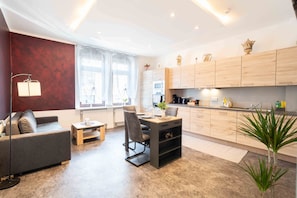 Un salon moderne avec un canapé, une table à manger et des chaises, une cuisine dotée de meubles en bois et une petite plante.