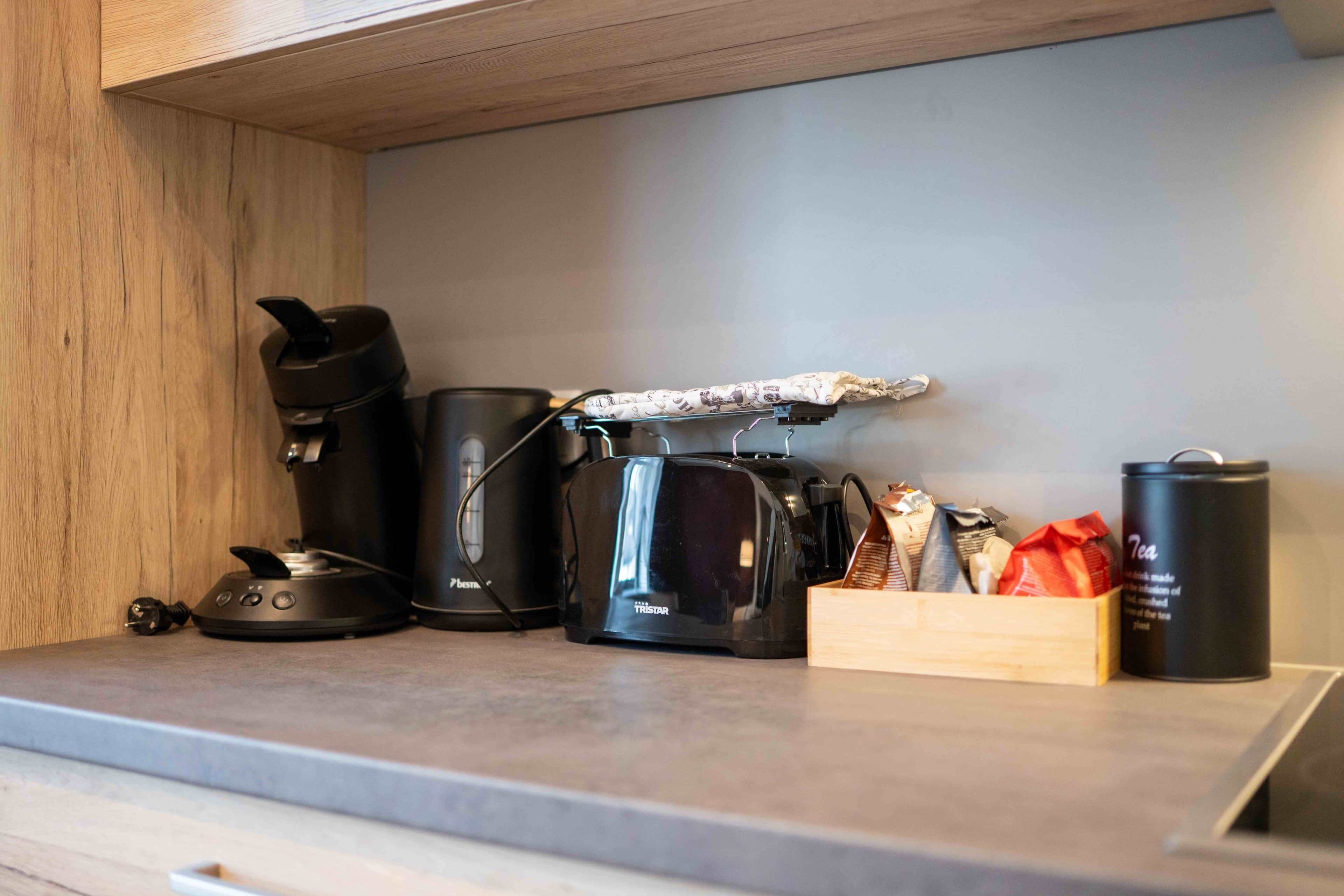 Un piano di lavoro in cucina con una macchina da caffè, un tostapane e una scatola di snack.