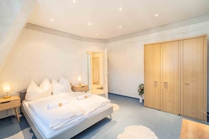Ein Schlafzimmer mit einem Bett, Nachttischen, einem Kleiderschrank und einem Spiegel.