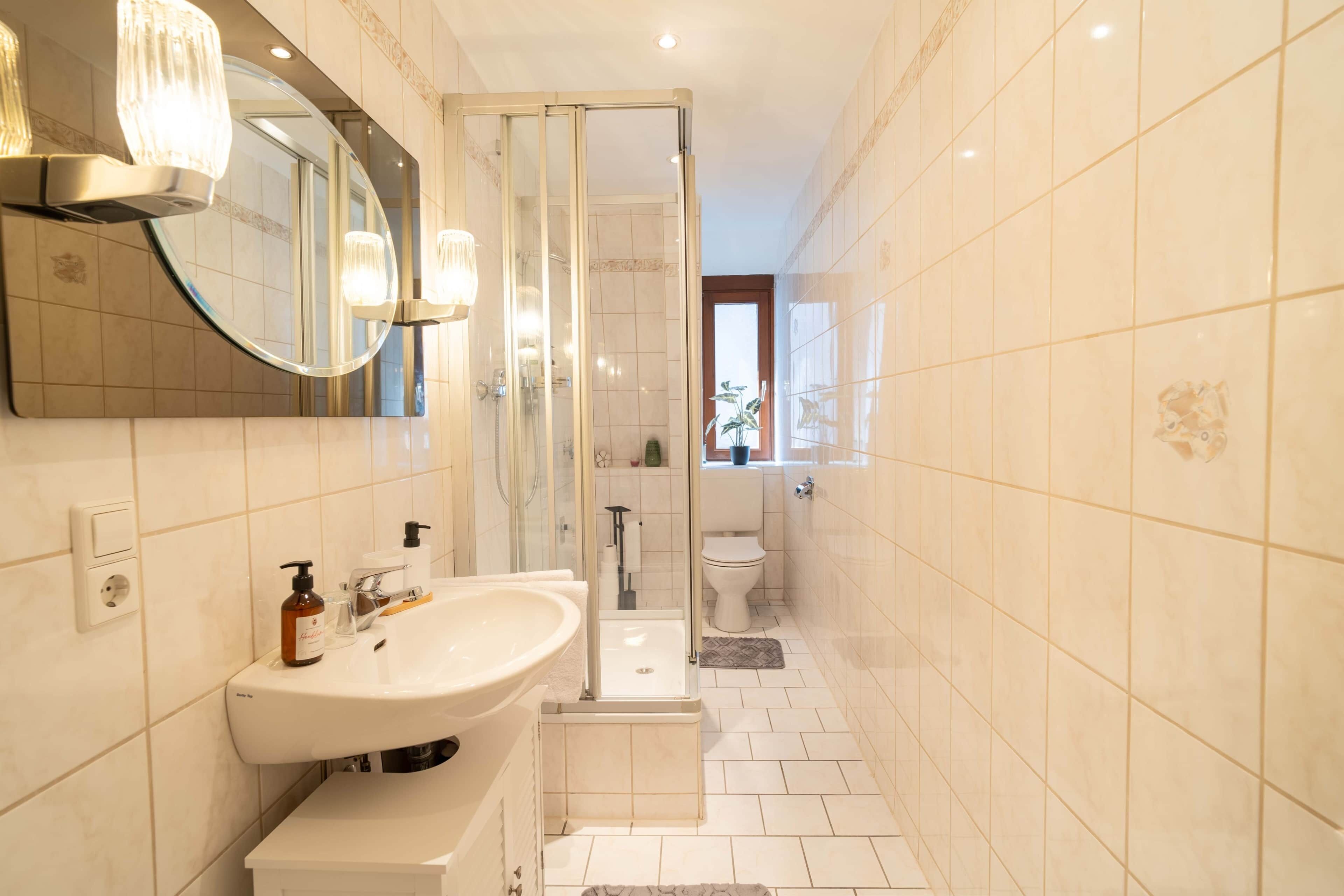 Ein modernes Badezimmer mit großem Spiegel, Waschbecken, Dusche und Toilette.