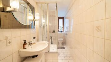 Ein modernes Badezimmer mit großem Spiegel, Waschbecken, Dusche und Toilette.