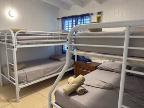 A bunk bed room with a wooden nightstand and a window with blue curtains. - Family-Friendly Townhouse | Pool & Outdoor Dining (Cobo Rojo)