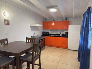A kitchen with orange cabinets, a stove, a sink, and a refrigerator. - Family-Friendly Townhouse | Pool & Outdoor Dining (Cobo Rojo)