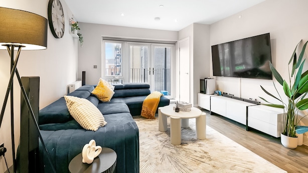 Una sala de estar moderna con un sofá modular, un televisor de pantalla plana, una mesa de centro y un amplio ventanal.