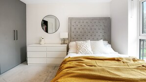 Un dormitorio con cama, cómoda, espejo y ventana.