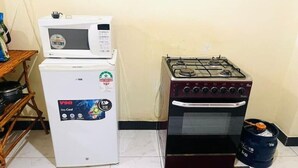 A compact kitchen with a refrigerator, microwave, gas stove, and a gas cylinder. - A clean studio Apartment in Nyali, Mombasa. (Mombasa)