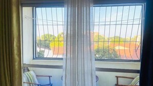 A room with a large window, a view of a red-roofed area, and two chairs with cushions. - A clean studio Apartment in Nyali, Mombasa. (Mombasa)