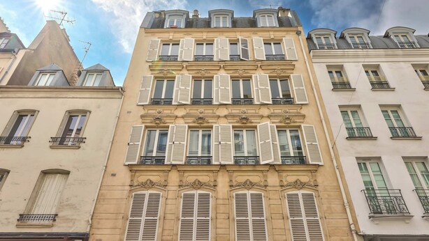 A multi-story building with a classic architectural style, featuring symmetrical windows and balconies. - Stylish 2BR in Private Mansion at Rue de Passy (Paris)