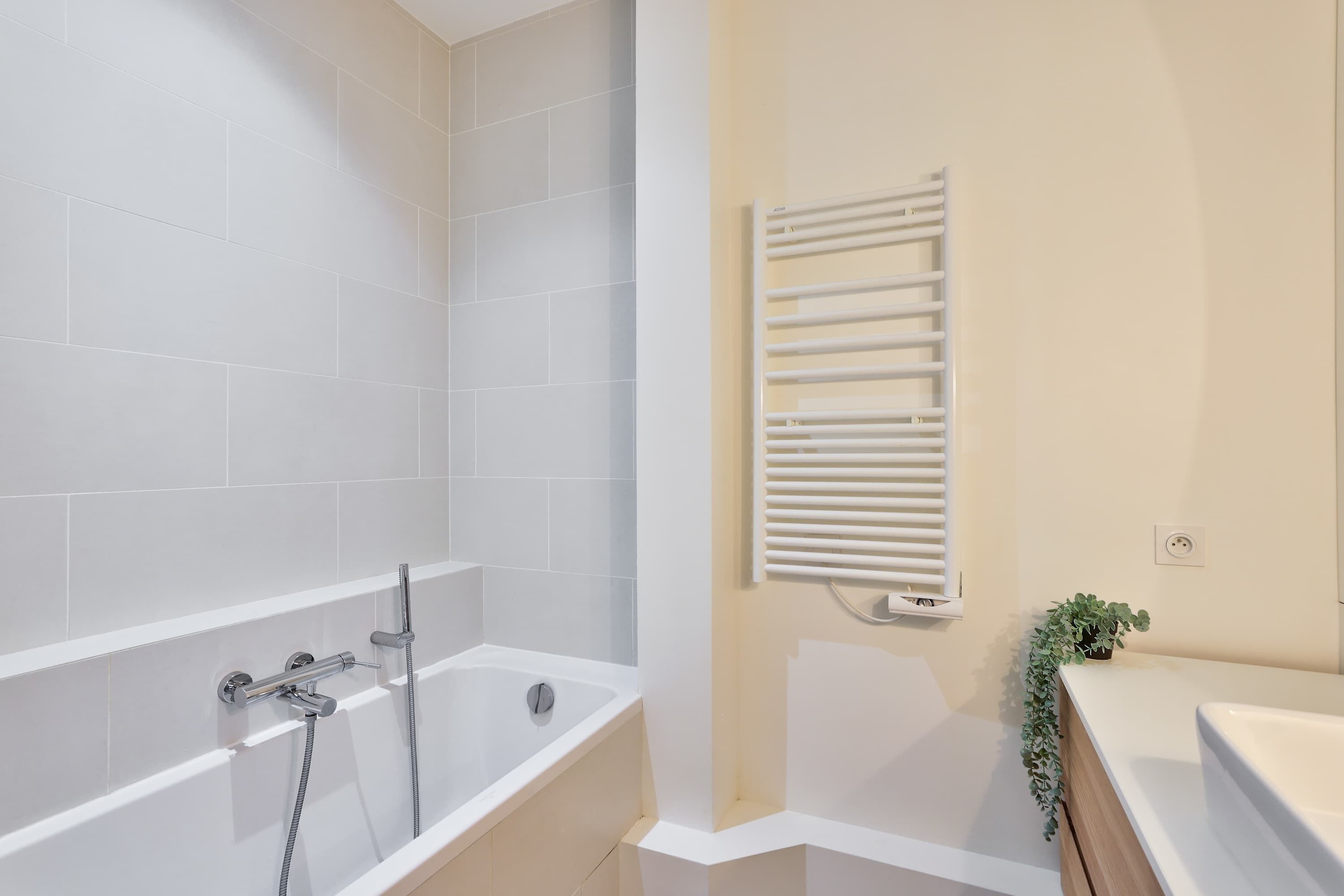 Une salle de bain moderne équipée d’une baignoire, d’une douche et d’un porte-serviettes.