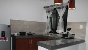 A kitchen with a refrigerator, stove, and utensils. - Departamentos Túumben Ché (Valladolid)