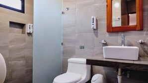 A bathroom with a toilet, sink, and mirror. - Departamentos Túumben Ché (Valladolid)
