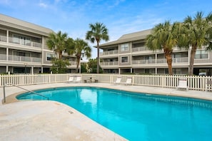 Un hôtel doté d’une piscine, de plusieurs balcons et de palmiers.