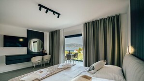Et moderne hotelværelse med en stor seng, et skrivebord med stole, et fjernsyn og en balkon med udsigt.